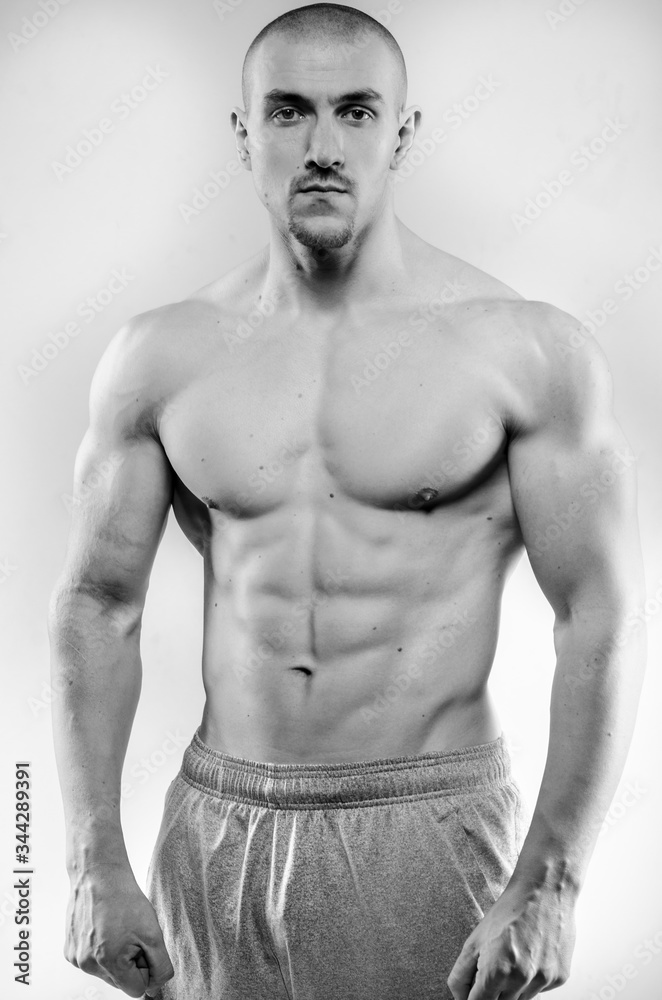 Naklejka premium Sporty guy posing in the Studio on the background. Sports, beauty, black and white photography