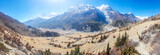 A panoramic view on Manang valley from Praken Gompa, Nepal. High Himalayan ranges around. There is a small lake in the valley. Snow capped peaks of Annapurna Chain. Harsh landscape.