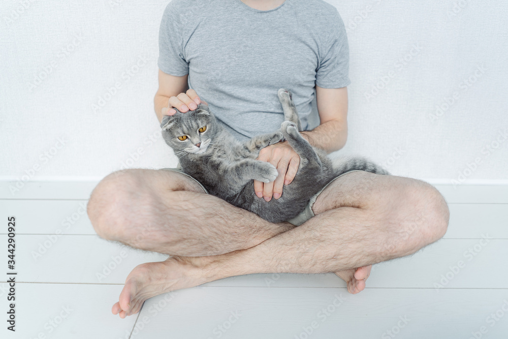 a man is sitting on the floor with a cat 