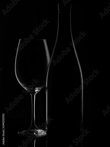 Glassed of red wine isolated on black background. Elegant red wine glass and a wine bottle. Bottle silhouette