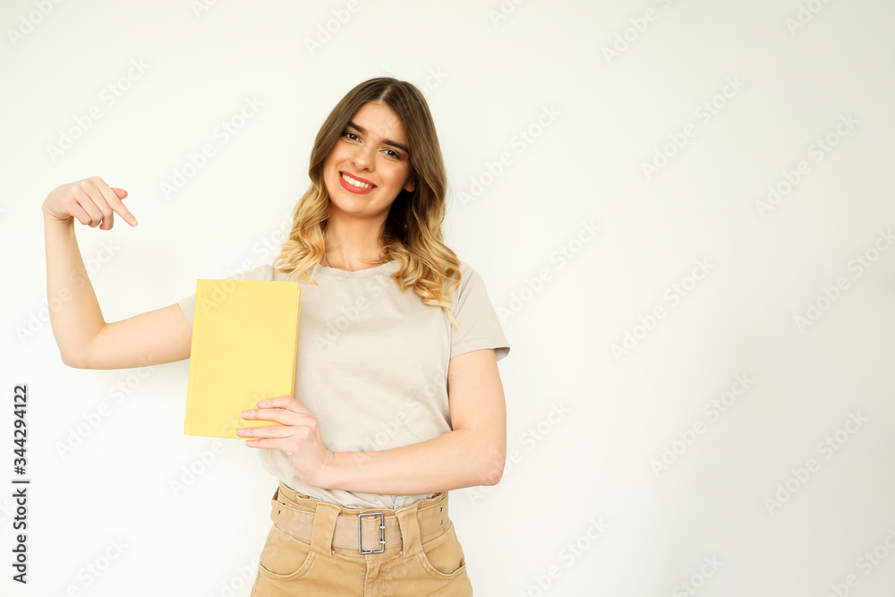 A young beautiful girl holding a yellow book template and pointing on o it. A young beautiful girl holding a yellow book template and pointing on o it.