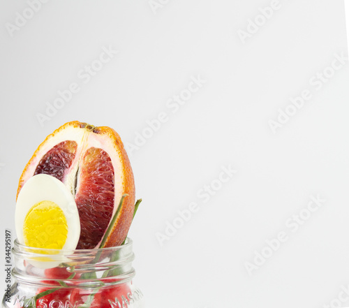 blood orange  hard boiled egg and chili peppers stuffed in a mason jar with copy space  on a soft white background