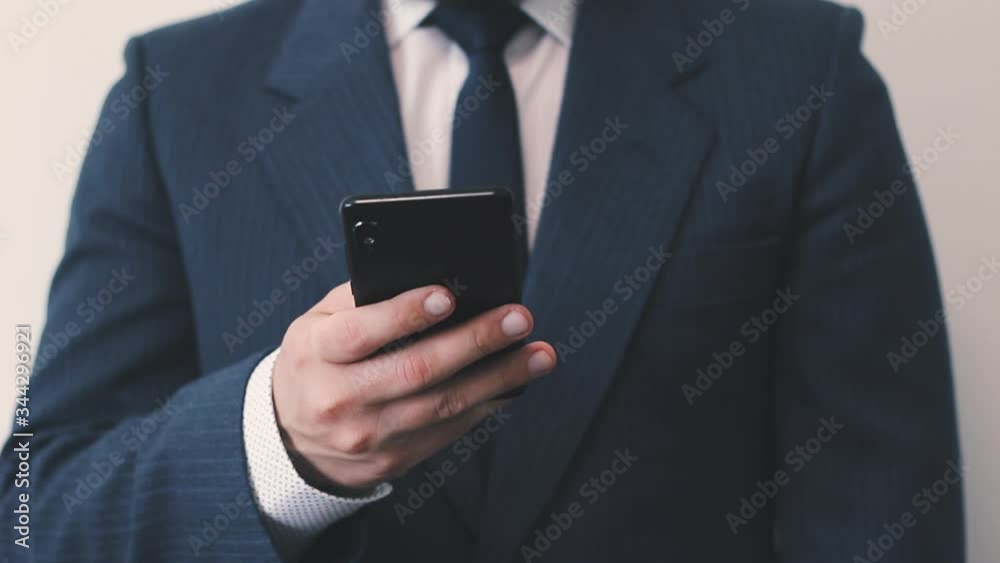 Businessman in blue suit uses his smartphone in hand, close up view Businessman in blue suit uses his smartphone in hand, close up view
