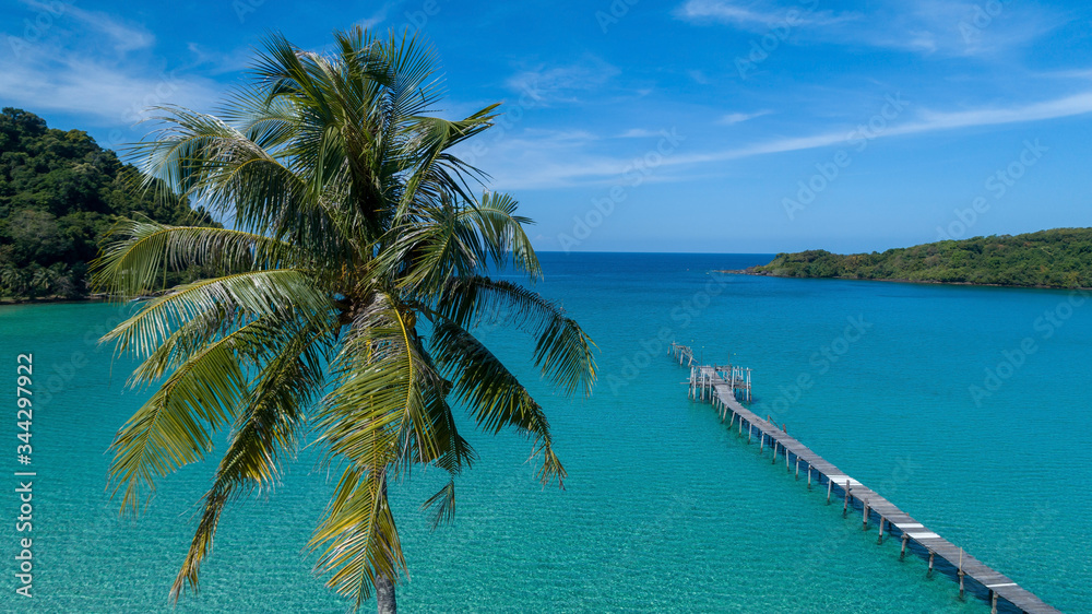 Coconut palm tree aerial drone view with pier in background on tropical paradise island in Koh Kood, Thailand