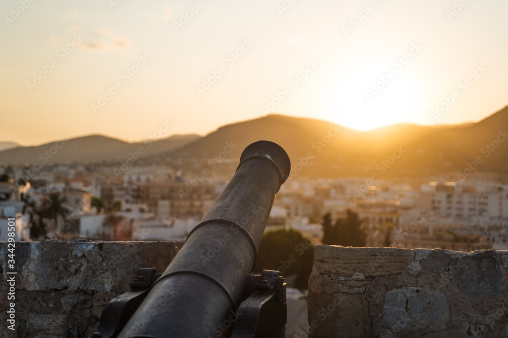 Beautiful scenery cannon of medieval fortress at sunset with view of mountains in Ibiza, Spain