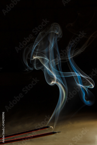 Puffs of smoke from a candle against a dark background