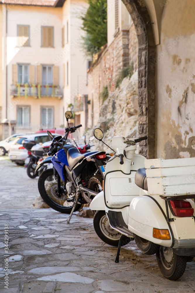 Parked motorbikes in the alley of historical town Bergamo, Lombardy, Italy.