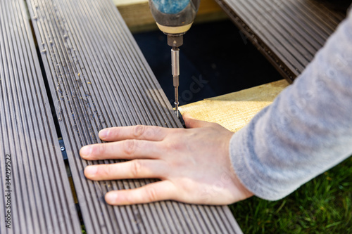 terrace deck construction - man installing wpc composite decking boards photo