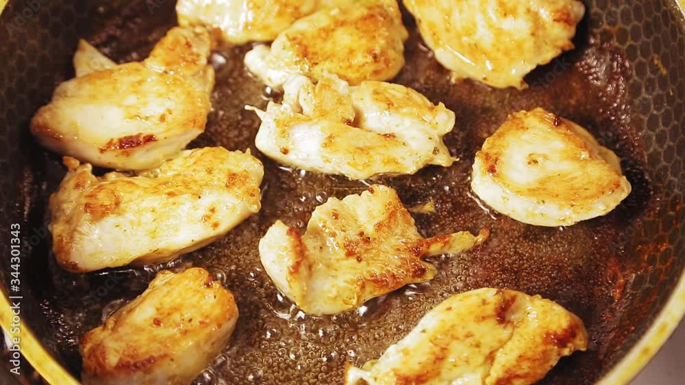 Chicken fillet with a crust is fried in boiling oil in a pan. Chicken fillet with a crust is fried in boiling oil in a pan.