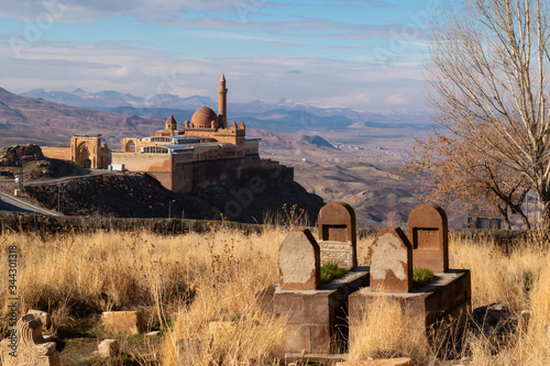 View of Ishak Pasha palace, with snowed mountains and a cementery with soe graves in Dogubayazit, Turkey photo