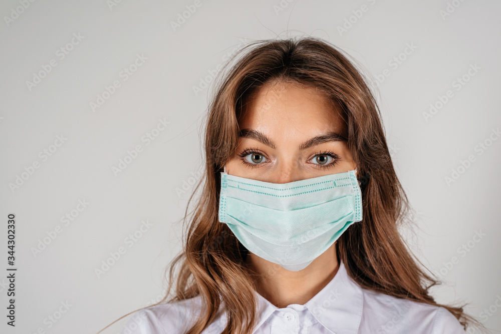 Young long-haired woman in protective medical mask over white background Young long-haired woman in protective medical mask over white background