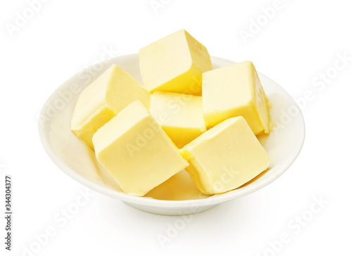 Butter pieces in white bowl isolated. Butter cubes.