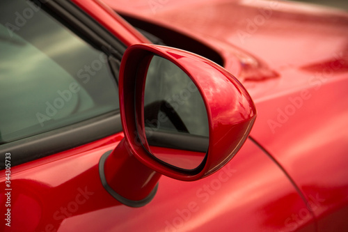 Rearview mirror. Part of a red car close up © Stasiuk