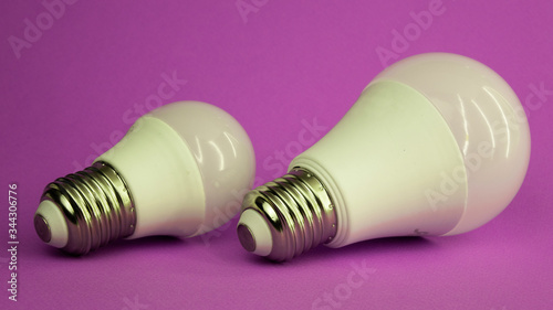 two white light bulbs of different sizes on a purple background photo