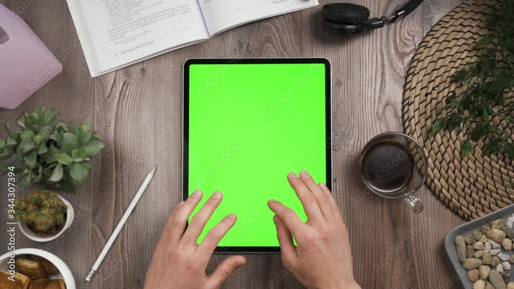 Vertical orientation big tab with green chromakey screen. Top view. Hands typing on the keyboard of touchscreen. Sends message. Workplace wooden table with many things. daylight. 4k video.