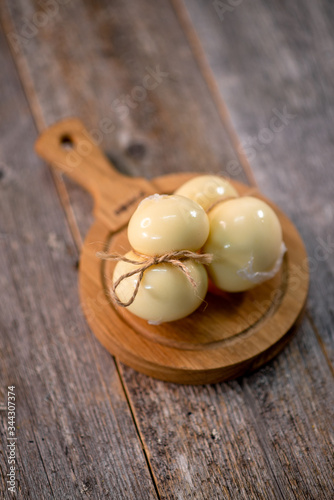Medium hard cheese head scamorza on wooden board with knife wooden texture daylight