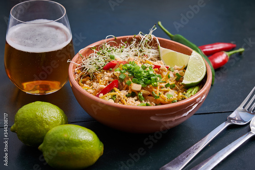 Valokuvatapetti Plate with spicy noodles with a glass of beer on a dark wooden table