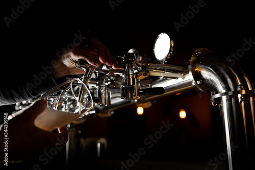 Beer tap in bar, mock up with selective focus. Hand of bartender pouring a beer in tap. Pouring beer for client.