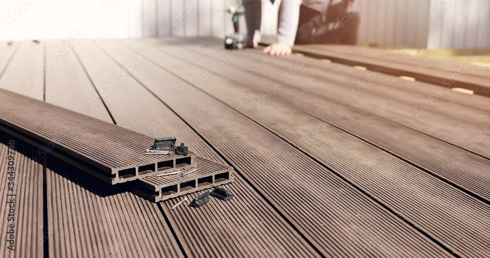 wpc terrace construction - worker installing wood plastic composite decking boards