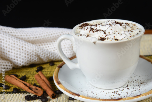 cup of coffee with milk and whipped cream on the table with roasted coffee beans