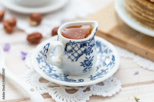 Nice blue and white cup full of fresh honey on a white table.