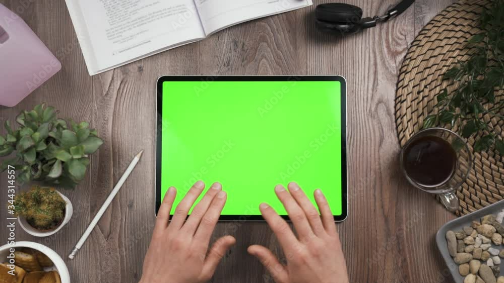 Horizontal orientation big tab with green chromakey screen. Top view. Hands typing on the keyboard of touchscreen. Sends message. Workplace wooden table with many things. daylight. 4k video.