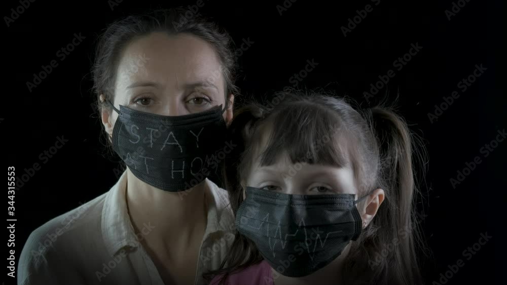 Home in quarantine. Portrait of mother and daughter wearing black protective masks. Protect yourself from the caronavirus. Home in quarantine. Portrait of mother and daughter wearing black protective masks. Protect yourself from the caronavirus.