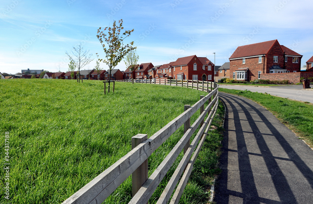 Wooden fence and field leading to a new housing estate