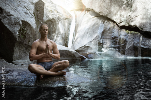 young athletic boy doing iodine and meditation in a waterfall
