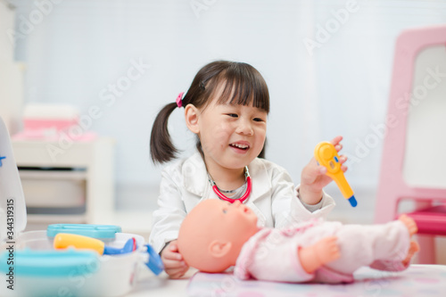 toddler girl pretend play  doctor role at home against white background