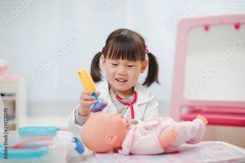 toddler girl pretend play  doctor role at home against white background