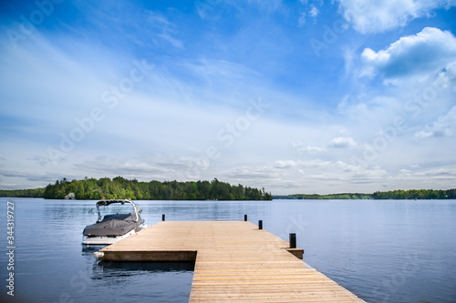 Photo Cottage lake view with boat docked on a wooden pier in Muskoka, Ontario Canada