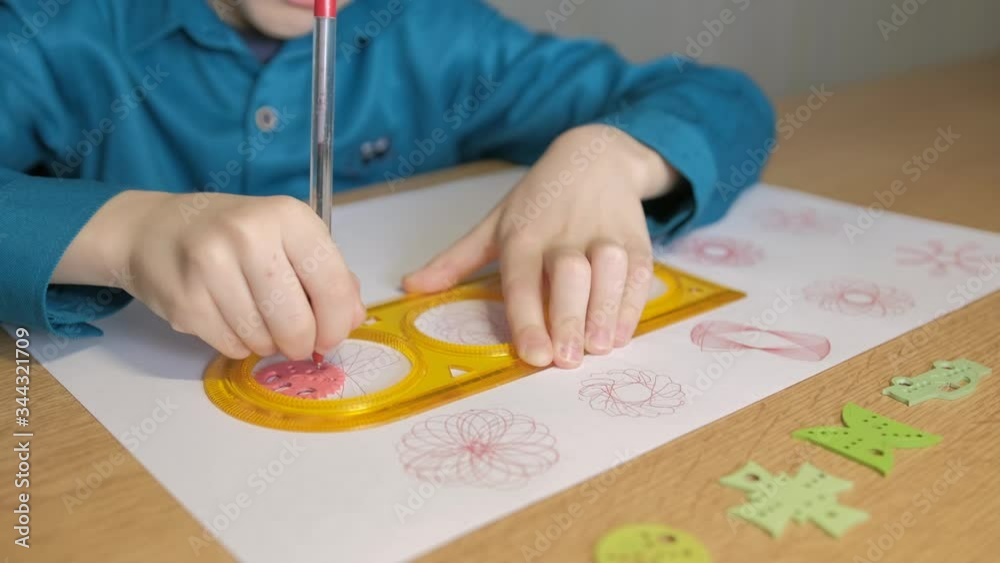 Teenager draws with red pen patterns, using the graphical ruler Teenager draws with red pen patterns, using the graphical ruler
