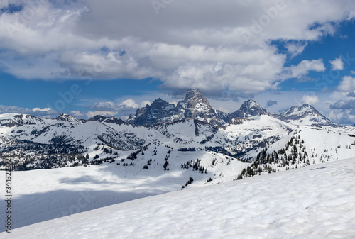 Eastern view of the Grand Tetons covered in snow with clouds and blue sky
