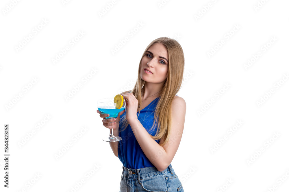 A girl in bright blue jeans and a blouse with a blue cocktail with lemon A girl in bright blue jeans and a blouse with a blue cocktail with lemon