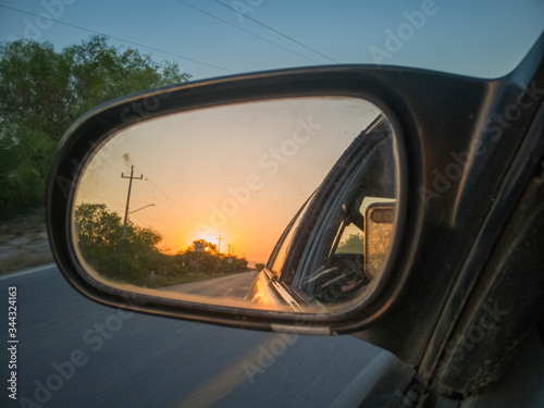 puesta de sol vista por el espejo izquierdo de un auto
