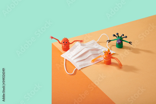 Corona Virus Covid 19 White particle face mask with germs cooties toys lined up on edge of table surface kid friendly image