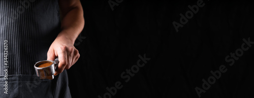 A man with a portafilter in his hands. The concept of making coffee in a coffee machine. Photo in a low key.