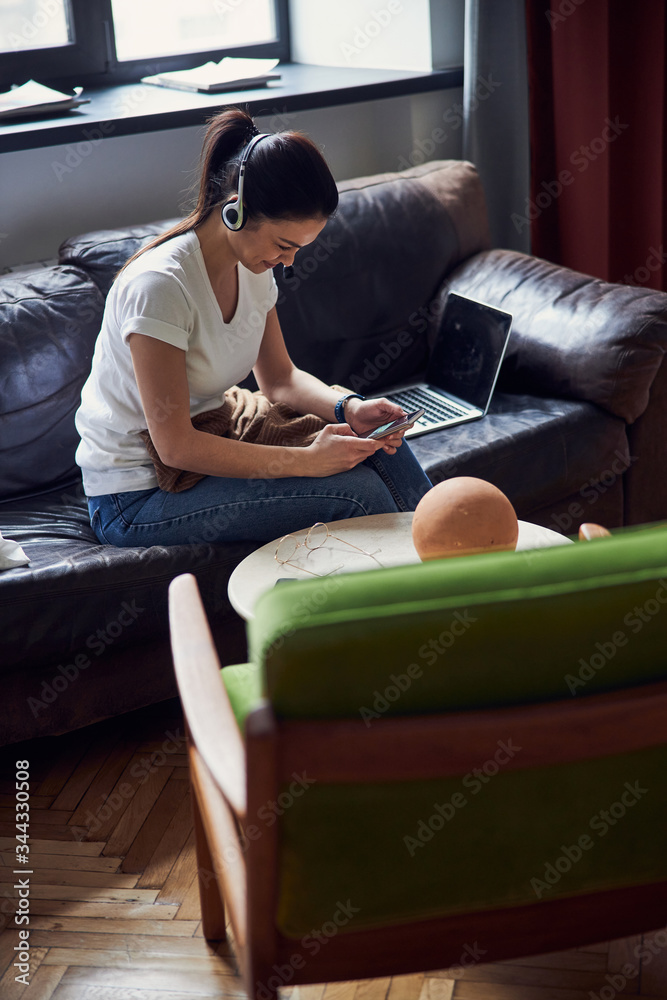 Caucasian woman typing sms while sitting on coach