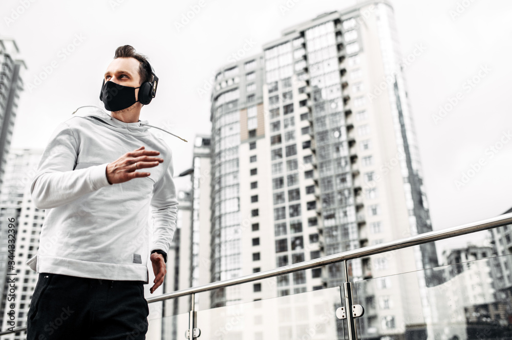 Keep fit during quarantine. Young athletic man in sportswear is running outdoors in urban landscape Keep fit during quarantine. Young athletic man in sportswear is running outdoors in urban landscape