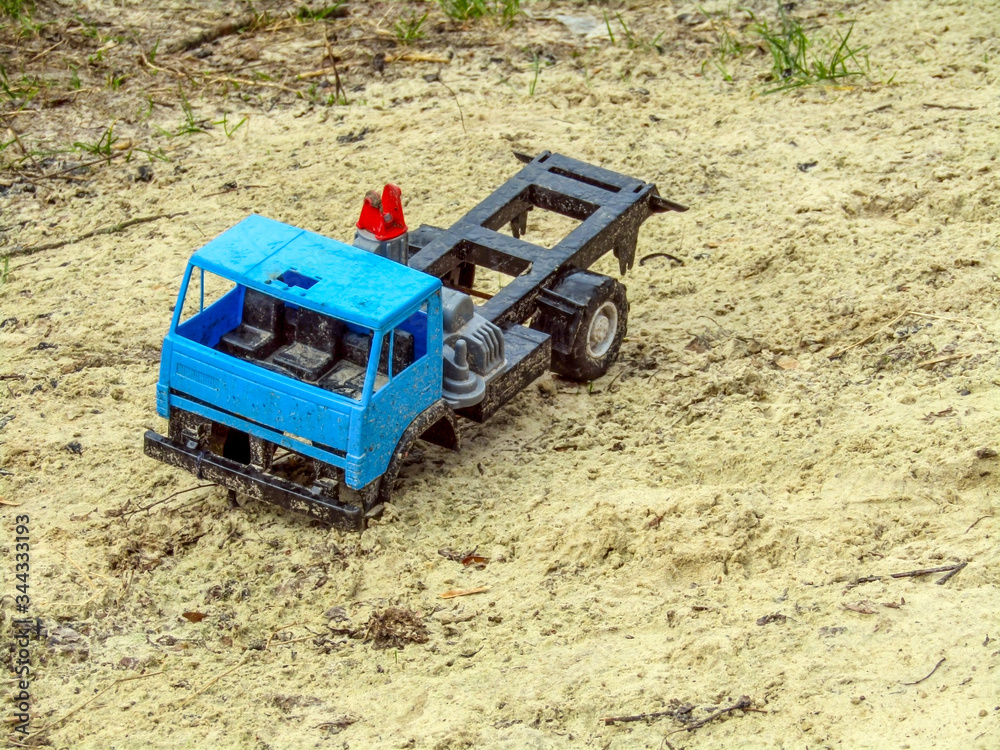 Broken toy car in the sand. Abandoned blue truck in the sandbox. photo Broken toy car in the sand. Abandoned blue truck in the sandbox. photo