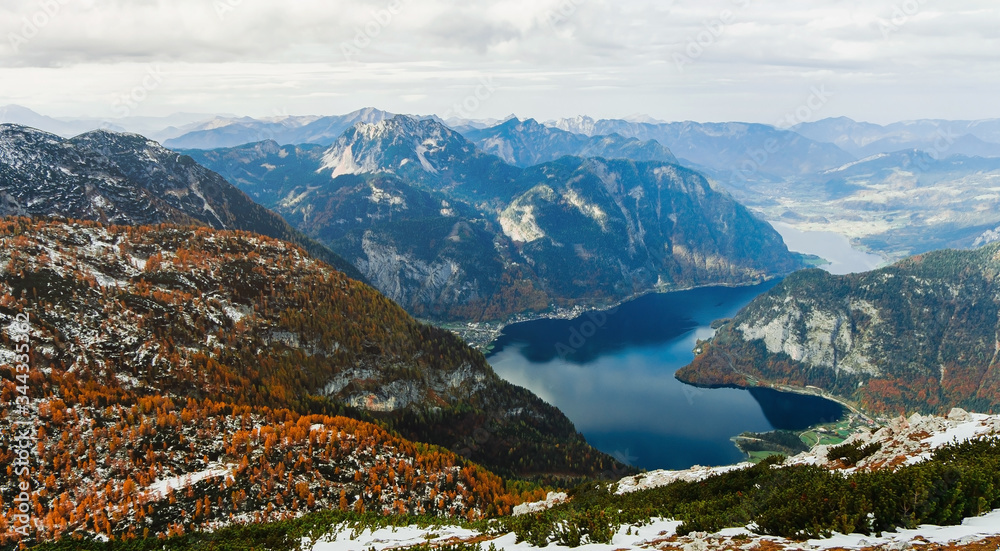View from above to Hallstatter lake and Hallstatt village among Alps mountains in Austria. Beautiful nature landscape. Autumn season and trees with orange colour. Wonderful valley and ridges.