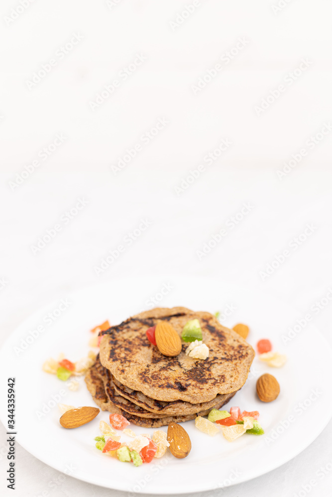 Homemade American pancakes with banana and dried fruits above white background