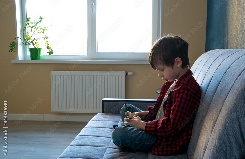 Focused boy enthusiastically plays in a smartphone. Leisure during self-isolation concept. Gadget dependence concept.