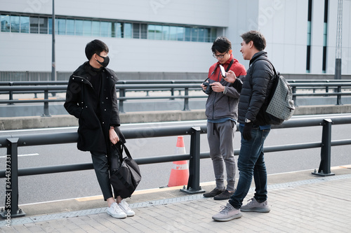 Social distancing of young people are waiting and wear protective face mask while talking together