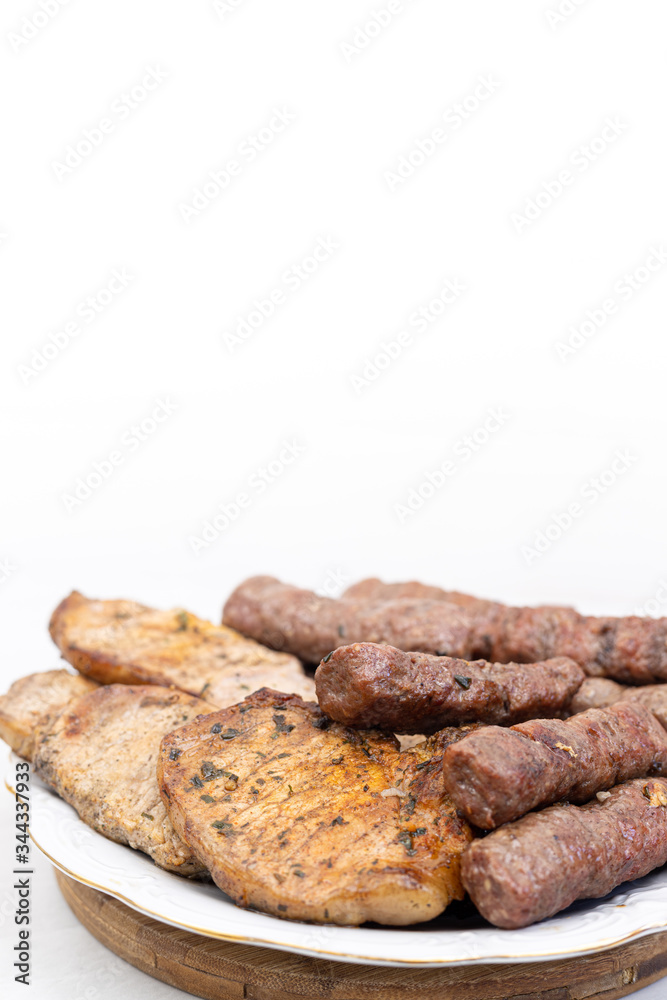 Mixed grilled meat on the plate. Grilled kebabs and pork chops served on the plate with copy space Mixed grilled meat on the plate. Grilled kebabs and pork chops served on the plate with copy space