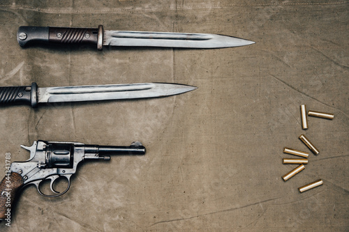 Bayonet knife with revolver Nagan system on an old surface in retro style. photo