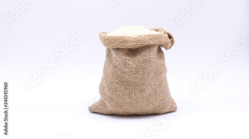 Closeup of white rice in a brown burlap sack isolated on white background