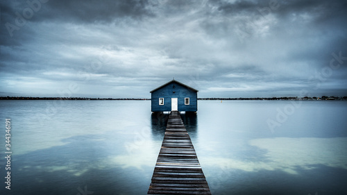 Blue boat shed on the river with cloudy sky