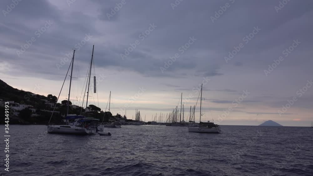 Sailing boats moored in Mediterranean sea. Mountain, trees and buildings. Lipari Islands, Sicily, Italy Sailing boats moored in Mediterranean sea. Mountain, trees and buildings. Lipari Islands, Sicily, Italy